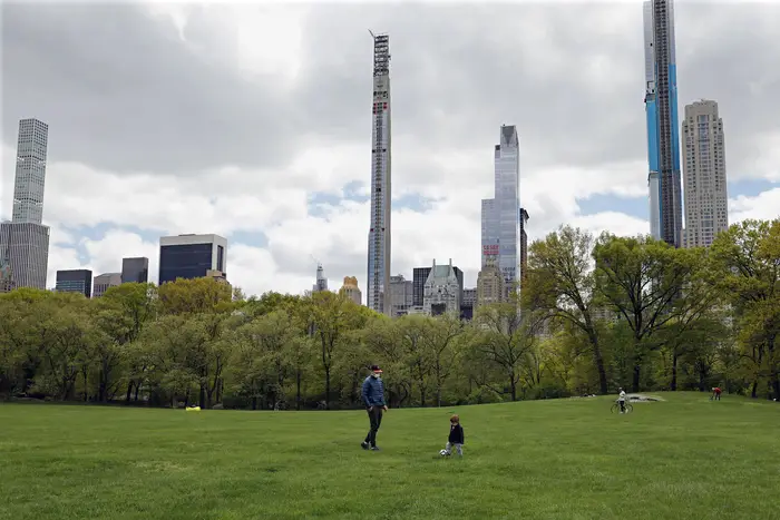 A father kicks around soccer ball with his young son in Central Park's Sheep Meadow in New York.